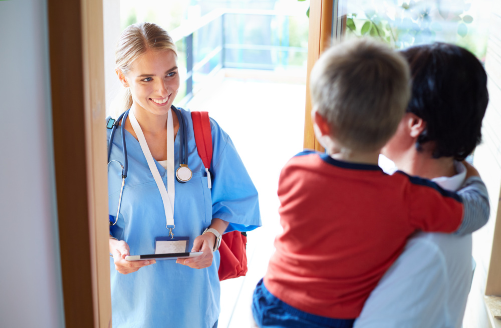 A nurse is talking to a child in front of a door.